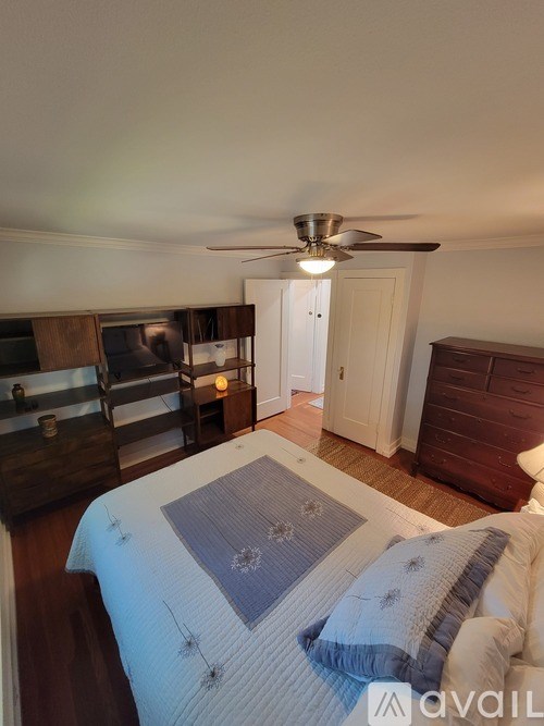 A bedroom with a bed, dresser, and ceiling fan.