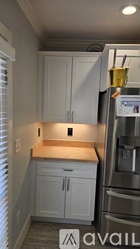 A kitchen with white cabinets and a stainless steel refrigerator.