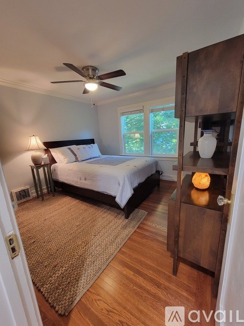 A bedroom with a bed, a ceiling fan, and a wooden cabinet.