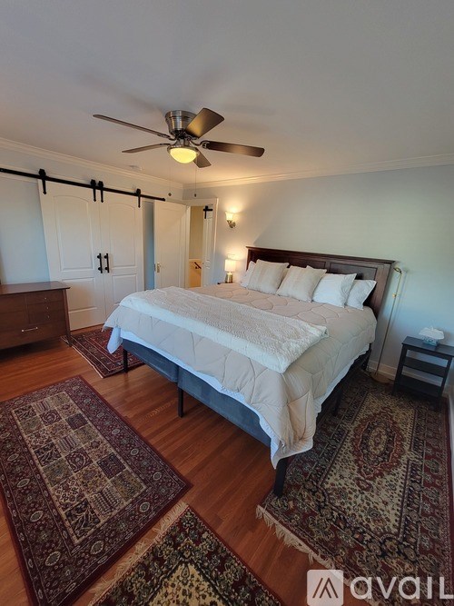 A bedroom with a bed, rug, and ceiling fan.