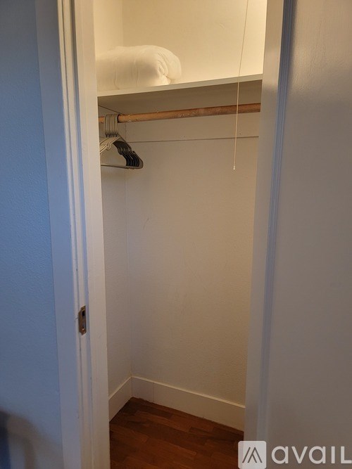 A white closet with a hanger on the rod.