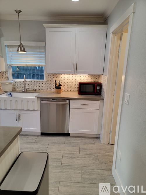 A kitchen with white cabinets and a microwave on the counter.