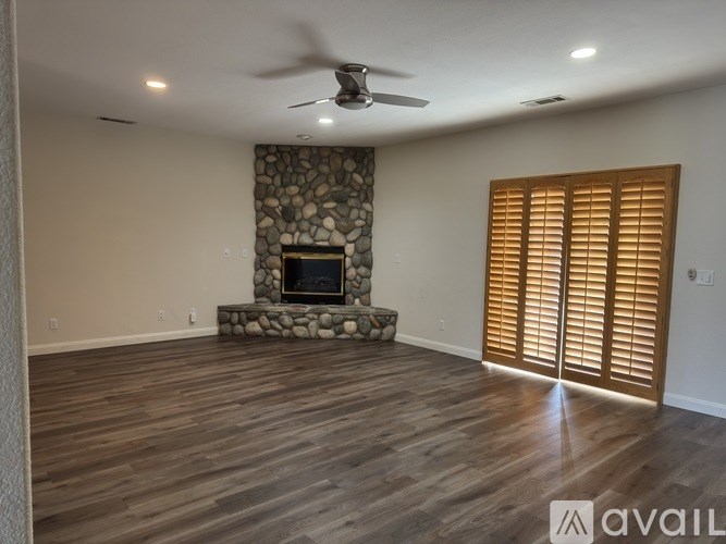 A room with a stone fireplace and wooden floors.