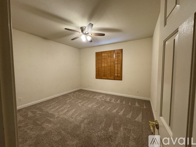 A room with a ceiling fan and carpeted floor.