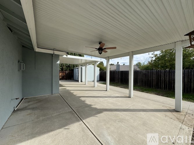 A covered patio with a ceiling fan and sliding glass doors.