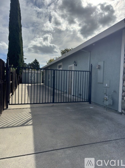A house with a black gate and a tree in front.
