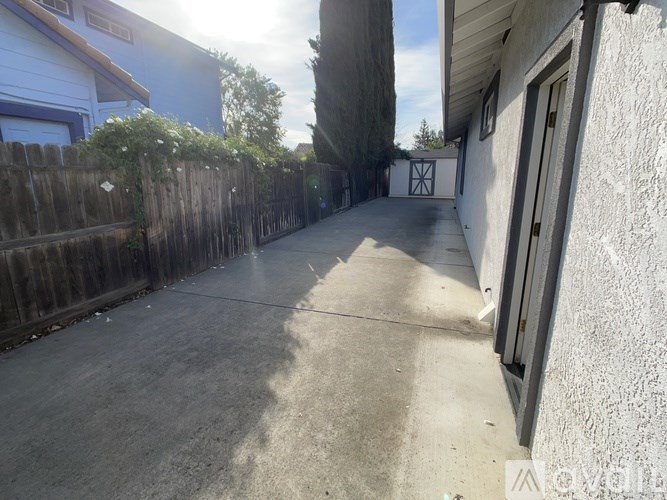 A sunny day in a residential area with a wooden fence and houses.