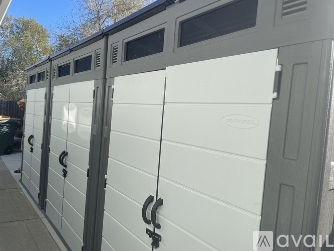 A row of white electrical boxes are lined up on a sidewalk.