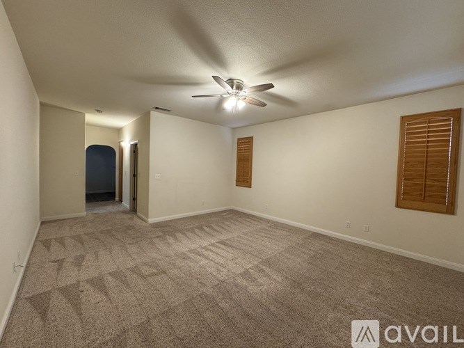 A spacious room with a carpeted floor and a ceiling fan.