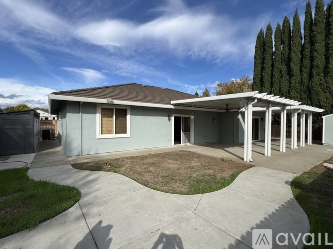 A house with a grey roof and a white pergola is for sale.
