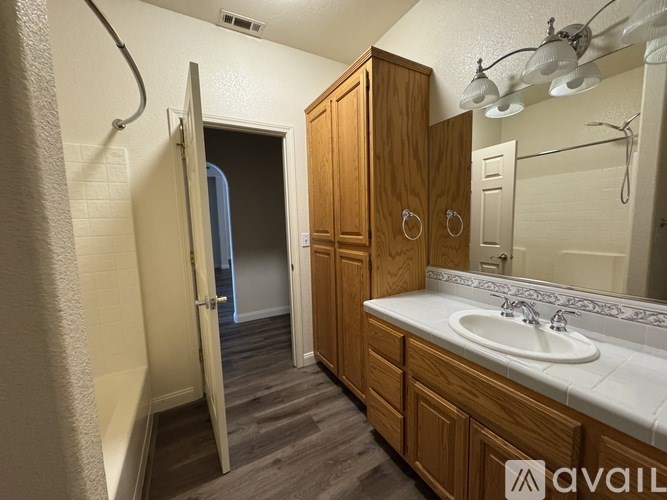 A bathroom with a sink, mirror, and wooden cabinets.