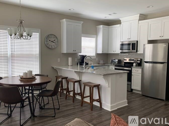 A kitchen with white cabinets and a center island with a marble top.