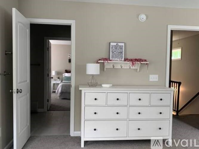 A white dresser with a lamp and a picture frame on top of it.