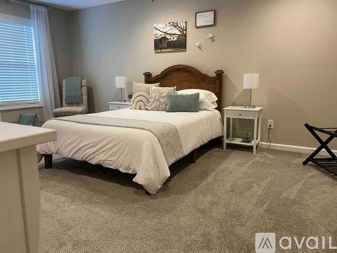 A bedroom with a large bed, a chair, and a nightstand.