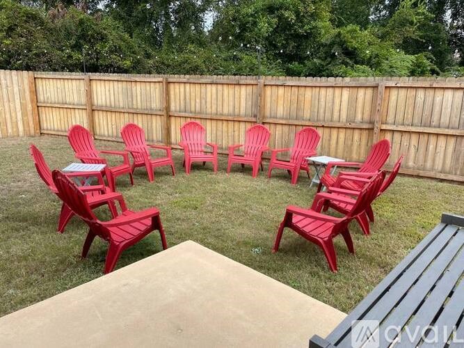 A set of red chairs and tables are arranged in a circle in a backyard.
