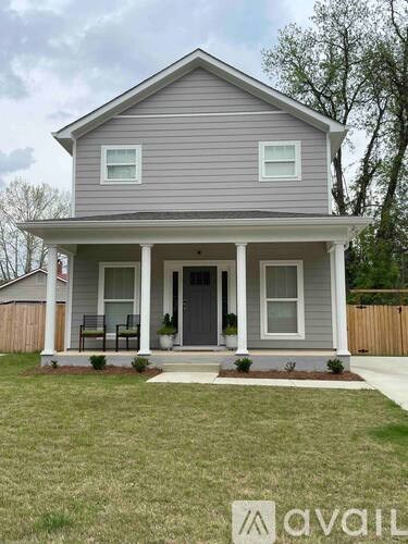 A house with a grey siding and a porch with a bench.