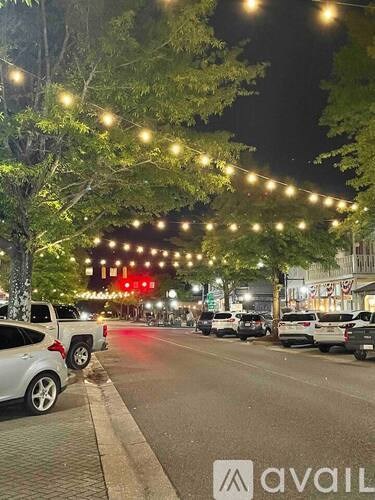A street lined with parked cars and decorative lights.