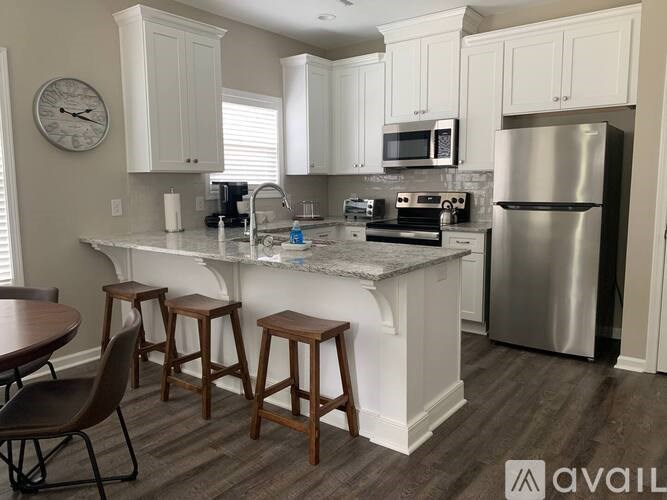 A kitchen with white cabinets and a marble countertop.