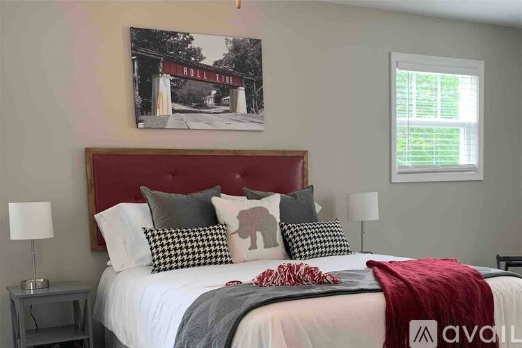 A bedroom with a bed, two lamps, and a painting of a Hollywood sign.