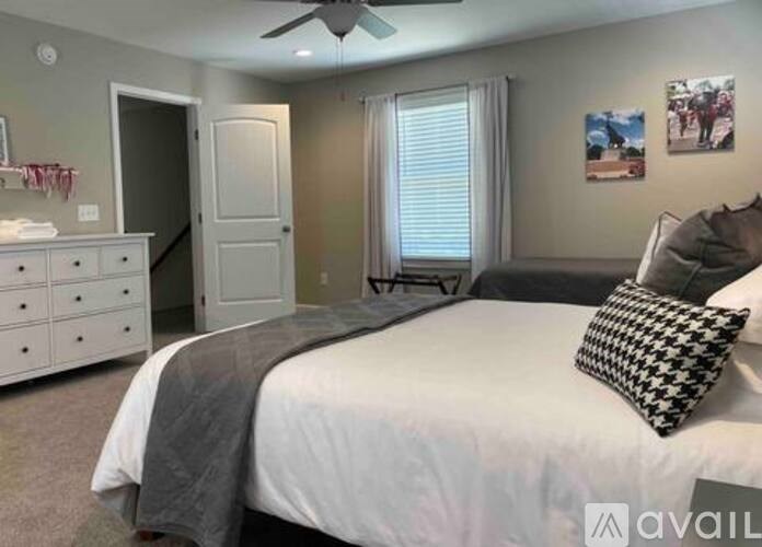 A bedroom with a bed, dresser, and a ceiling fan.