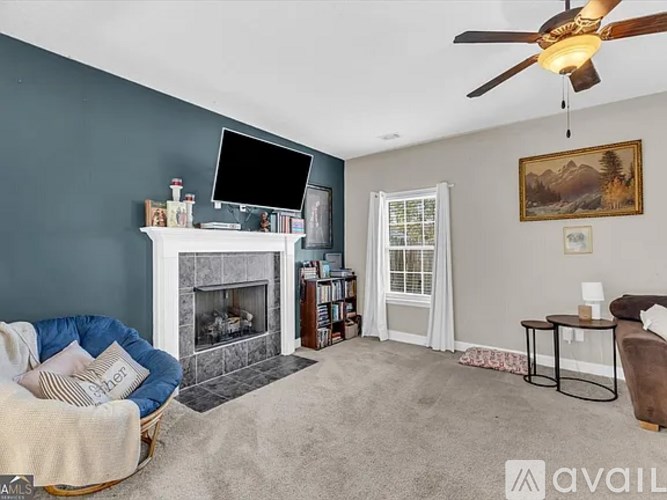 A living room with a fireplace, a television, a chair, and a painting on the wall.