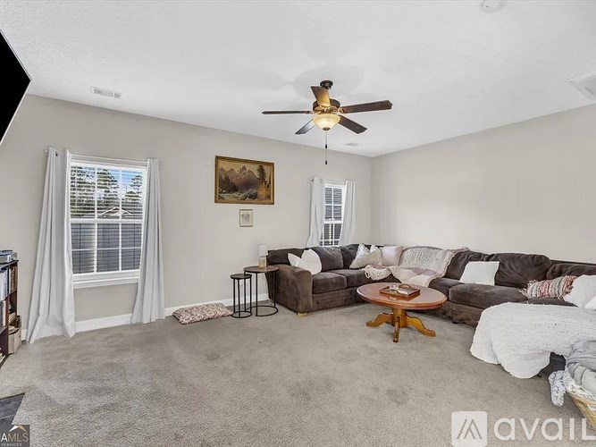 A living room with a brown couch, a coffee table, and a ceiling fan.