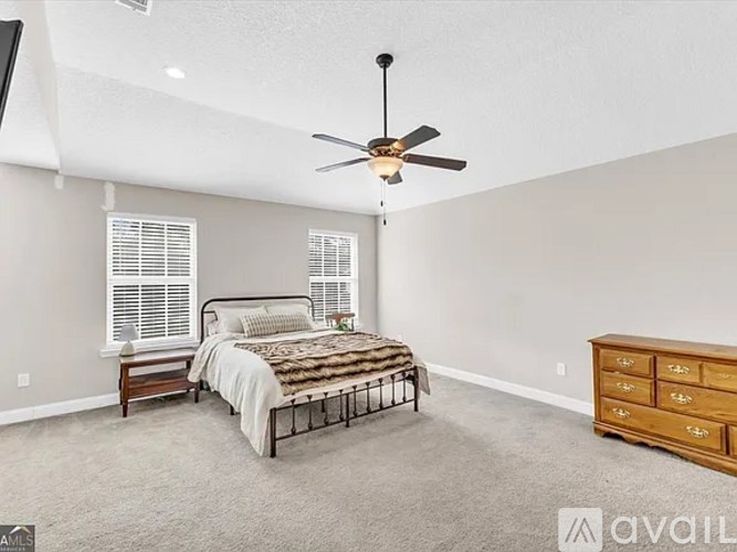 A bedroom with a bed, dresser, and ceiling fan.