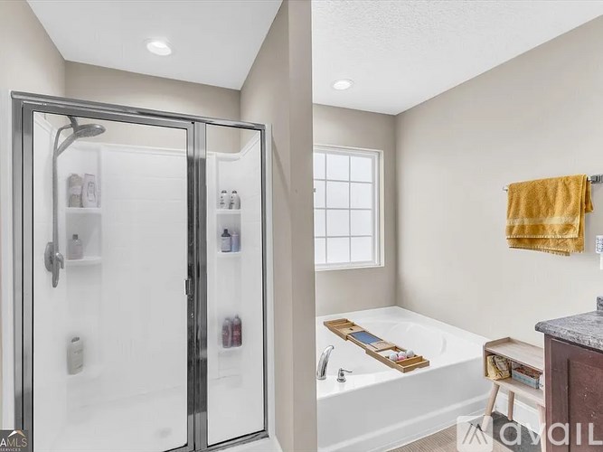 A bathroom with a glass shower door and a white bathtub.