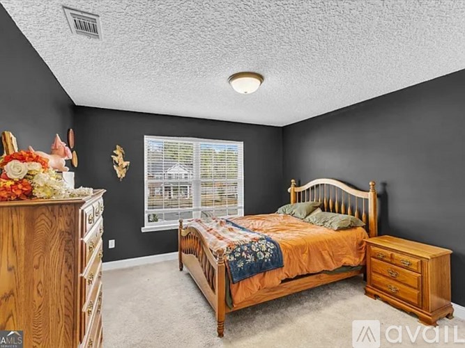 A bedroom with a bed, dresser, and window.