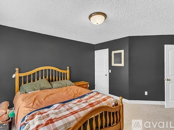 A bedroom with a bed, nightstand, and a window.