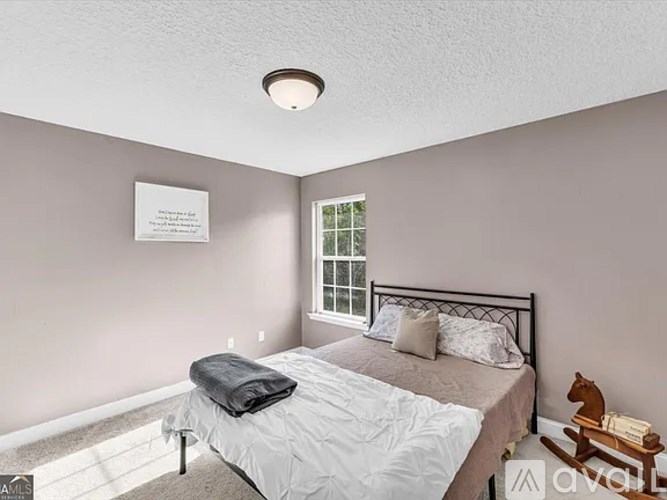A bedroom with a bed, a window, and a wooden rocking horse.