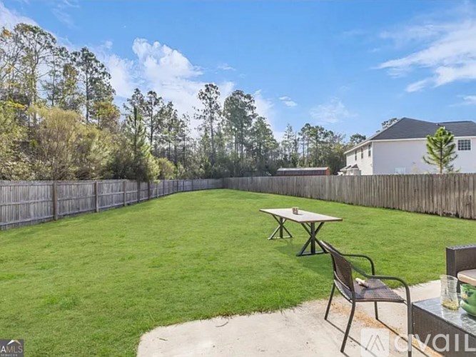 A backyard with a picnic table and a fence.