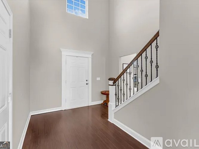 A room with a wooden floor and a staircase with a black railing.