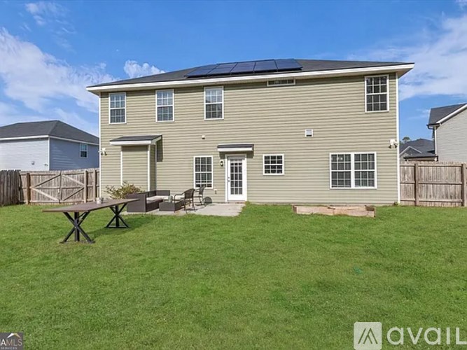 A house with a solar panel on the roof and a picnic table in the yard.