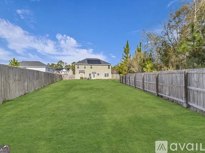 A backyard with a fence and a house in the background.