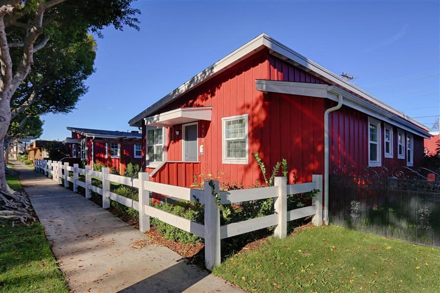 a red house with a white fence and a sidewalk