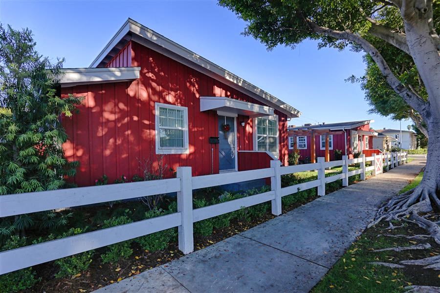 a red house with a white fence and a sidewalk