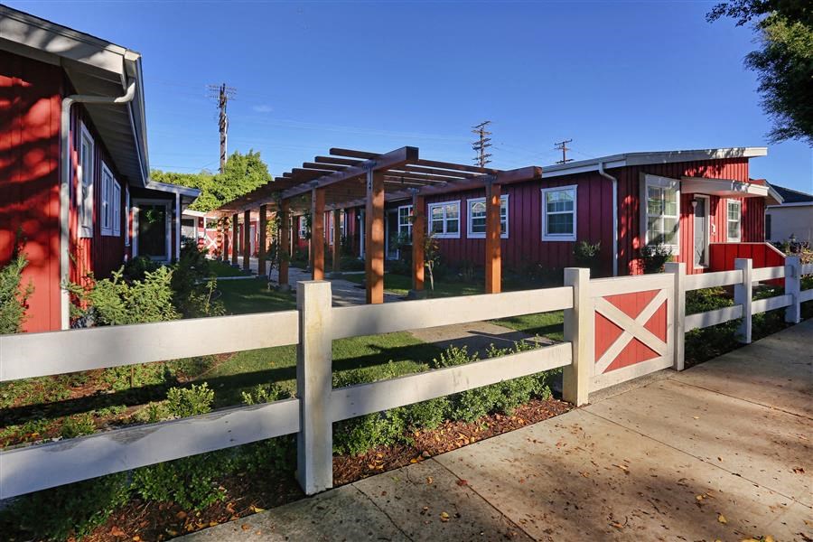 a row of red tiny houses in front of a white fence