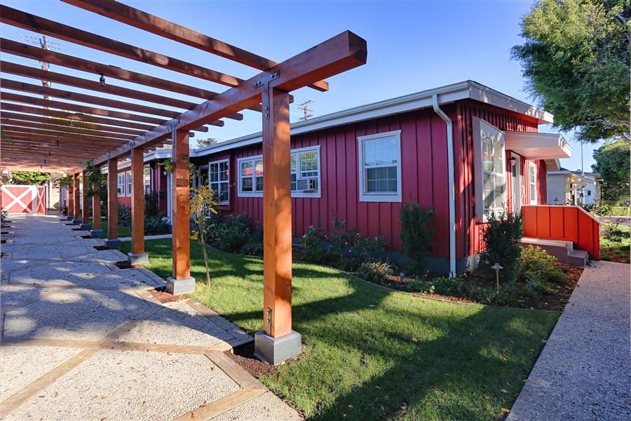 a red house with a covered porch and a sidewalk