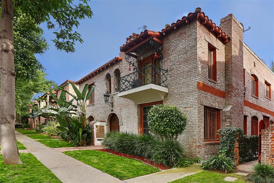 a brick house with a balcony and a sidewalk