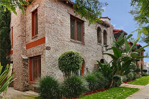 a brick building with a tree and plants in front of it