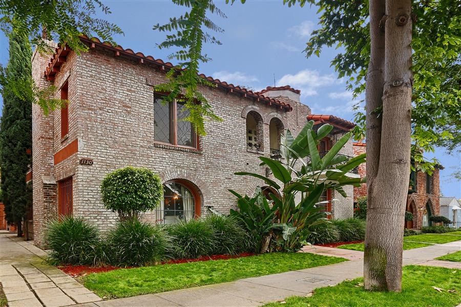a brick house with a sidewalk and plants