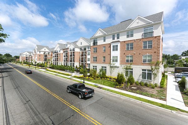 a car driving down a street in front of an apartment building
