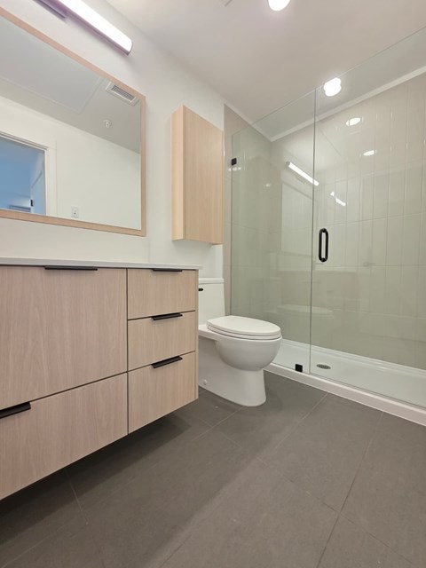 A white toilet sits in a modern bathroom with a glass shower door.
