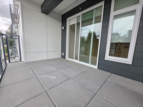 A patio with a grey tile floor and a white door.