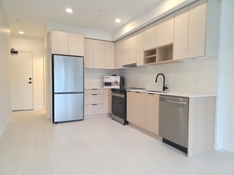 A kitchen with a refrigerator, sink, and stove.