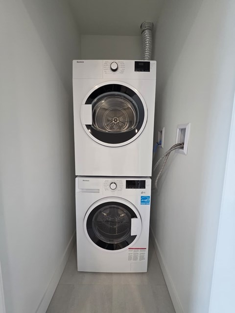 Two front loading washing machines in a narrow laundry room.