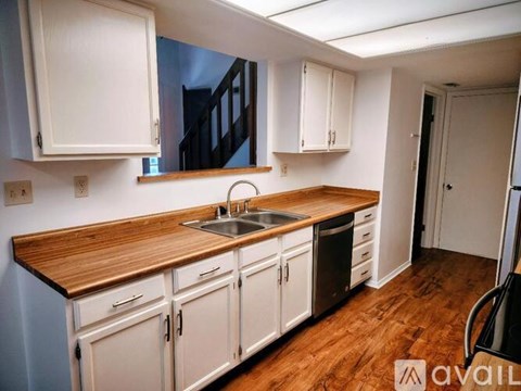 A kitchen with wooden countertops and white cabinets.