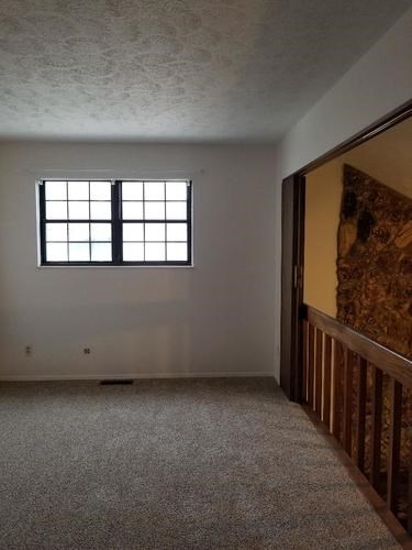 A room with a window and a carpeted floor.