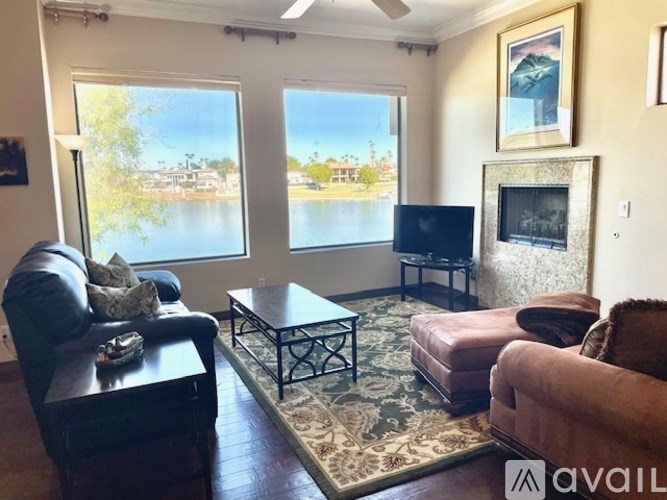 A living room with a large window overlooking a lake.